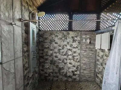 a bathroom with a shower with a stone wall at Pitangus Lodge in Chachagua