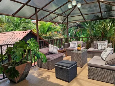 a patio with wicker furniture under a canopy at Pitangus Lodge in Chachagua