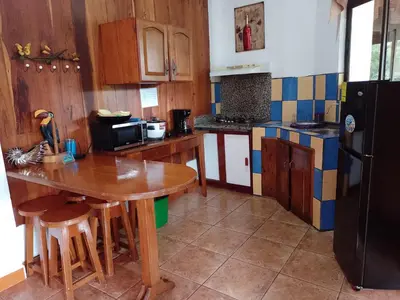 a kitchen with a wooden table and a black refrigerator at Natural Pacific Suites, Manuel Antonio-Quepos-Hotel in Manuel Antonio