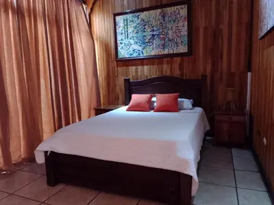 a bedroom with a bed with white sheets and red pillows at Natural Pacific Suites, Manuel Antonio-Quepos-Hotel in Manuel Antonio