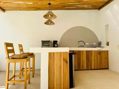 a kitchen with a counter and a sink and chairs at Las Guapas Villas Tamarindo in Tamarindo