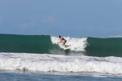 a man riding a wave on a surfboard in the ocean at Casa de la Naturaleza in Cóbano