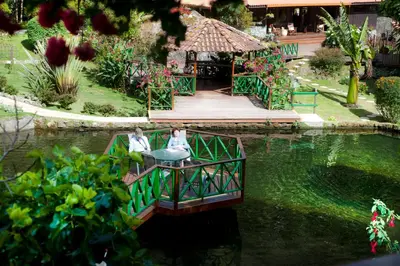 two women sitting on a bridge over a pond at Trogon Lodge in San Gerardo de Dota