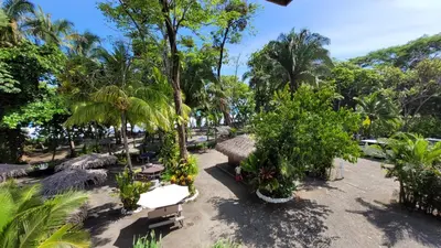a resort with palm trees and tables and chairs at Buena Vista Plus in Quepos