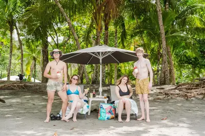 a group of people sitting under an umbrella on the beach at Buena Vista Plus in Quepos