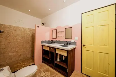 a bathroom with a sink and a toilet and a yellow door at Casita Mar Y Posa in Potrero