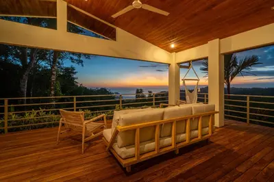 a porch with a bed and a chair on a deck at Casa Frenchie with Private Guesthouse - by Pura Villas in Dominicalito