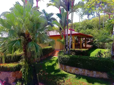 a house with palm trees in front of a yard at Casi el Cielo - by Pura Villas in Uvita