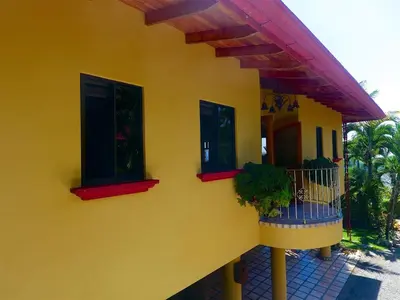 a yellow house with two windows and a balcony at Casi el Cielo - by Pura Villas in Uvita