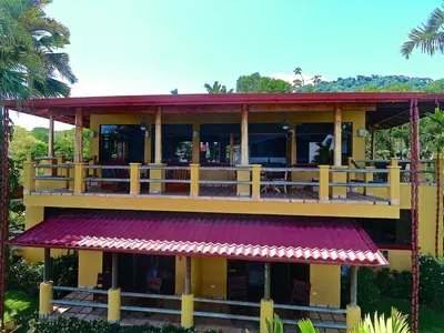 a yellow building with a balcony and a restaurant at Casi el Cielo - by Pura Villas in Uvita