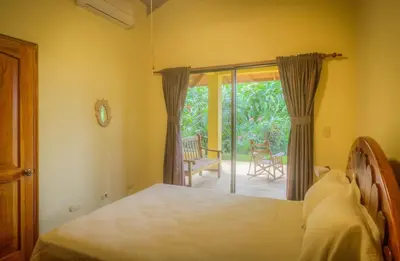 a bedroom with a bed and a sliding glass door at Casi el Cielo - by Pura Villas in Uvita