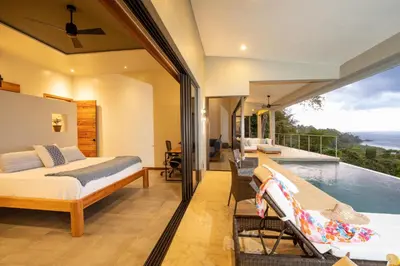 a bedroom with a bed and a swimming pool at Casa Ola Vista - by Pura Villas in Dominicalito