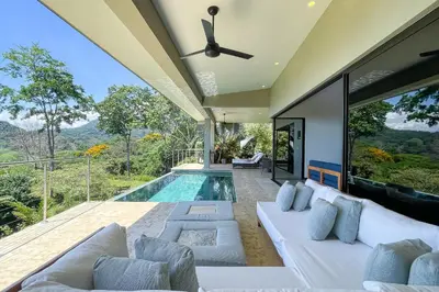 a living room with a white couch and a pool at Casa Ola Vista - by Pura Villas in Dominicalito