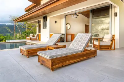 two lounge chairs on a patio next to a pool at Casa Grande del Mar - by Pura Villas in Punta Mala