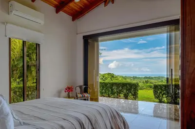 a bedroom with a bed and a large glass window at Hacienda Jaguar - by Pura Villas in Ojochal