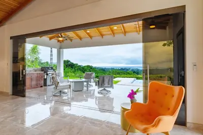 an open kitchen and dining room with sliding glass doors at Hacienda Jaguar - by Pura Villas in Ojochal