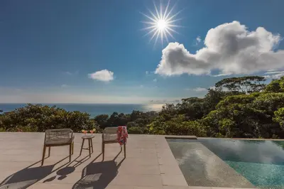 two chairs and a table next to a swimming pool at Casa ReSol - by Pura Villas in Uvita