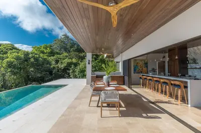 an outdoor kitchen and dining area with a pool and a house at Casa ReSol - by Pura Villas in Uvita