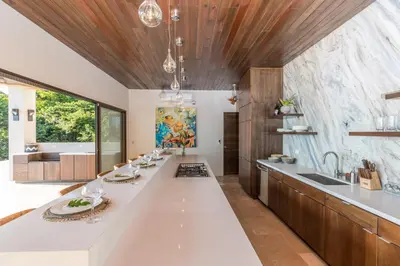 a kitchen with a large white counter top and wooden ceilings at Casa ReSol - by Pura Villas in Uvita