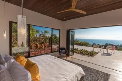 a bedroom with a large bed and large windows at Casa ReSol - by Pura Villas in Uvita