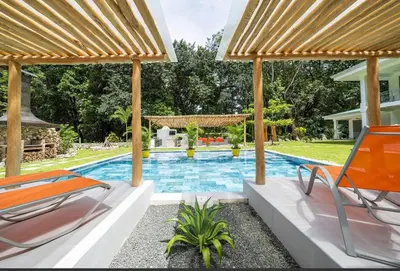 a swimming pool with two chairs and a house at Villa Harmonia in Potrero