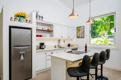 a kitchen with white cabinets and a stainless steel refrigerator at Buendía Lux Mango Suite Stylish Retreat with Pool Near Beach in Potrero