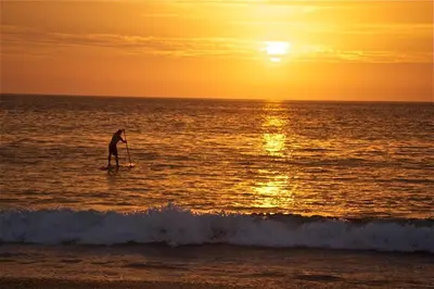 a person standing on a paddle board in the ocean at Plaza Mercado 22 At Las Catalinas in Playa Danta