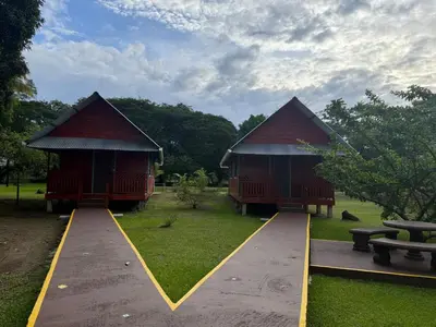 two small huts in a park with a bench at Cabinas Tortuguero Sports Fishing in Tortuguero