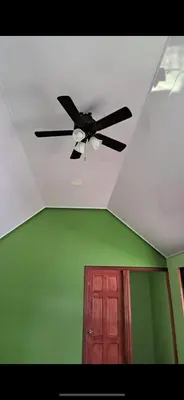 a ceiling fan in a room with a door at Cabinas Tortuguero Sports Fishing in Tortuguero