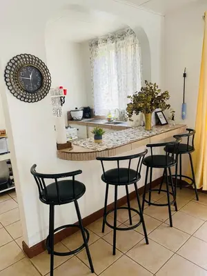 a kitchen with a counter with four stools at a table at Mahale House - Manuel Antonio, Quepos in Quepos