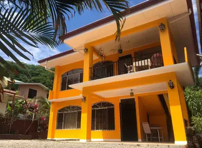 a yellow and white house with a balcony at Mahale House - Manuel Antonio, Quepos in Quepos