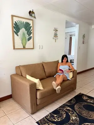 a woman sitting on a couch reading a book at Mahale House - Manuel Antonio, Quepos in Quepos