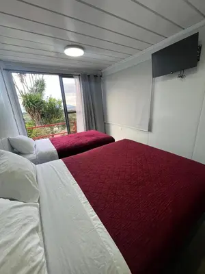 a bedroom with two beds and a large window at Hotel Hospedaje Alto Lechuza Zarcero in Zarcero
