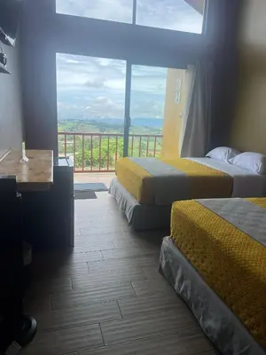 a hotel room with two beds and a balcony at Hotel Hospedaje Alto Lechuza Zarcero in Zarcero
