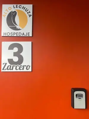 an orange wall with a sign and a number on it at Hotel Hospedaje Alto Lechuza Zarcero in Zarcero