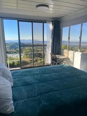 a bedroom with a large bed with a large window at Hotel Hospedaje Alto Lechuza Zarcero in Zarcero