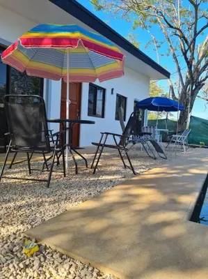 a group of chairs and umbrellas in front of a house at Casa Mar de Sueños Tamarindo in Tamarindo