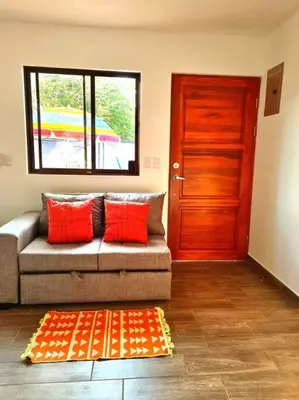 a living room with a couch with red pillows and a door at Casa Mar de Sueños Tamarindo in Tamarindo