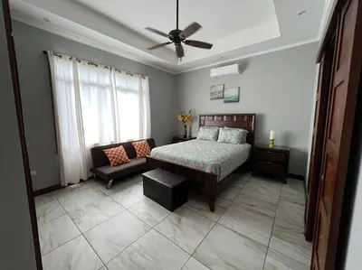 a bedroom with a bed and a couch and a ceiling fan at Casa Famari at Playa Bejuco in Bejuco