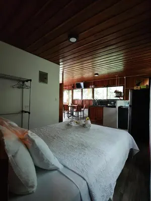 a bedroom with a white bed and a kitchen at Gambas Lodge in Fortuna