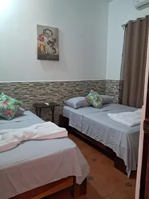 a room with two beds and a painting on the wall at Casa Eli en Playa Manuel Antonio in Quepos