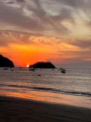 a sunset on the beach with boats in the water at Mariposa End Unit Loft in Coco