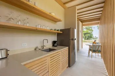 a kitchen with a stainless steel refrigerator and a table at New Beachfront House - Casa Aura in Santa Teresa Beach