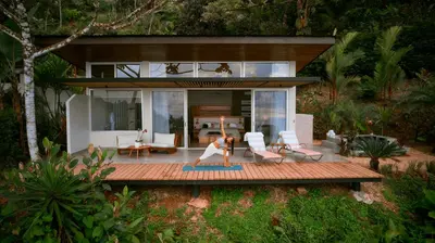 a woman is practicing yoga on a deck in front of a house at Vista Celestial in Uvita