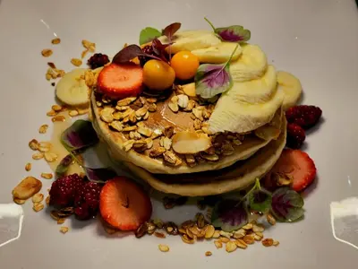 a stack of pancakes with fruit and nuts on a plate at Vista Celestial in Uvita