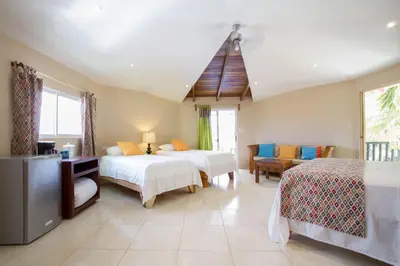 a bedroom with two beds and a living room at Tamarindo Village Hotel in Tamarindo