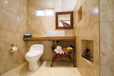 a bathroom with a toilet and a sink and a mirror at Tamarindo Village Hotel in Tamarindo