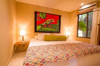 a bedroom with a bed with a painting on the wall at Tamarindo Village Hotel in Tamarindo