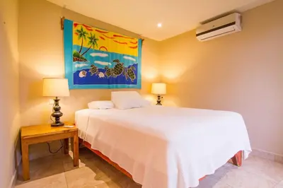 a bedroom with a white bed and a painting on the wall at Tamarindo Village Hotel in Tamarindo