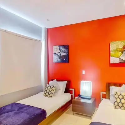 a bedroom with two beds and an orange wall at Jaco Bay 4903 Three bdrm Suite Spectacular Views Pool in Jacó
